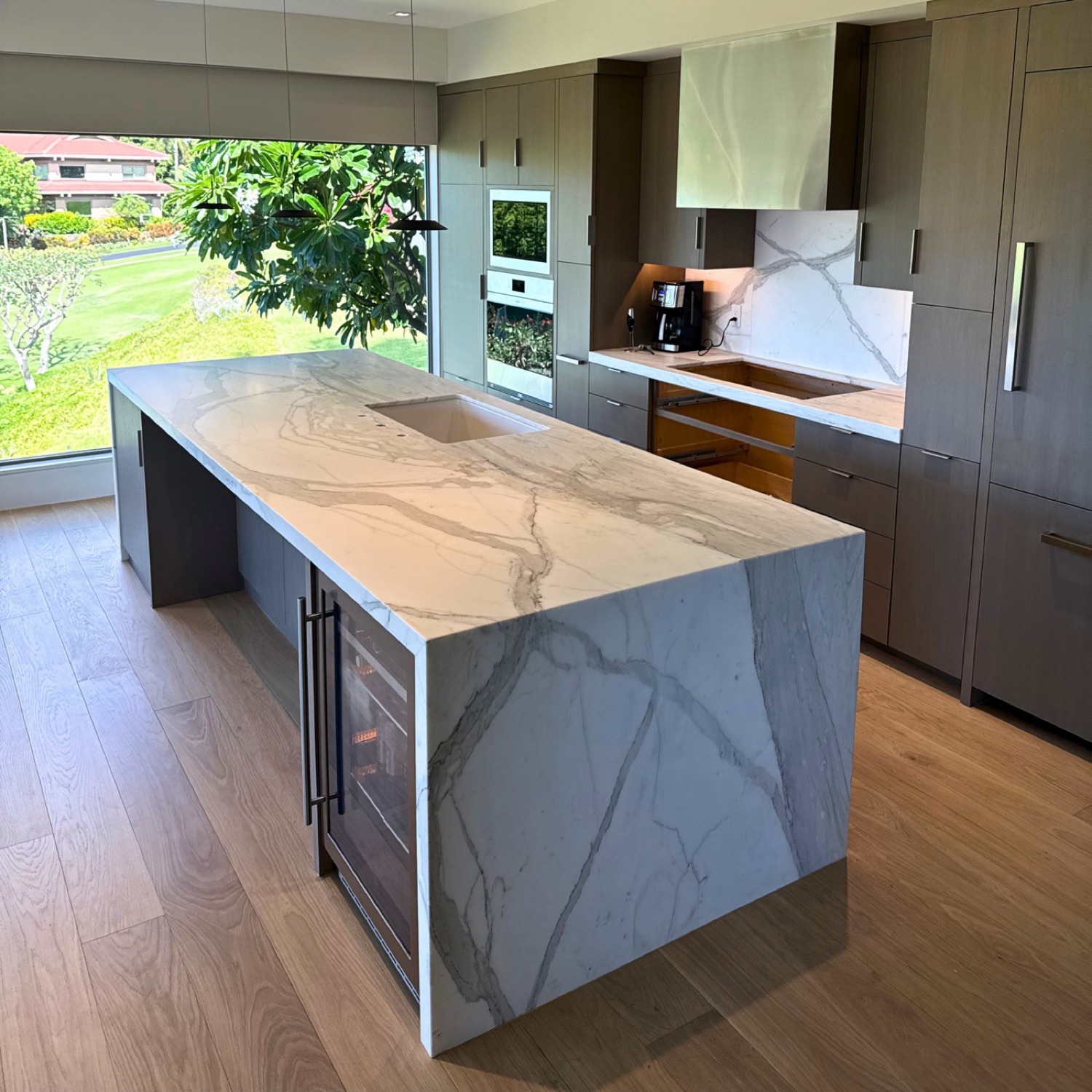 Calacatta marble waterfall island with a mitered edge, treated at the slab before fabrication